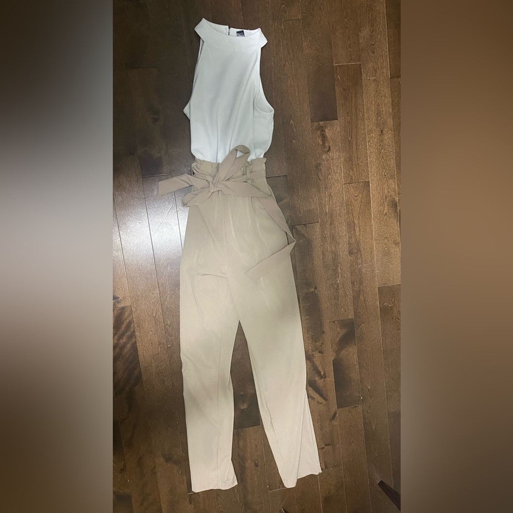 Beige and white long romper style jumpsuit with a halter top and keyhole back.